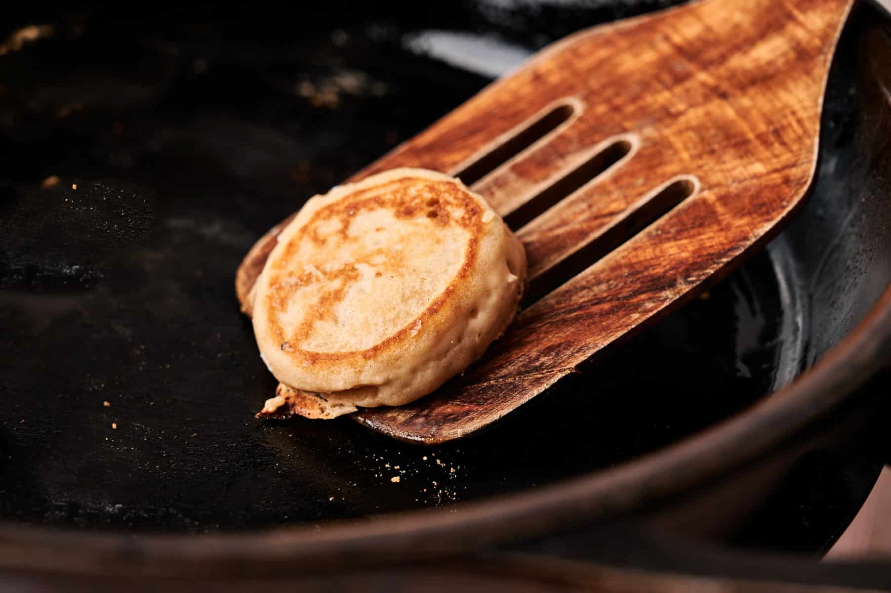 Flipping mini pancakes on a cast iron skillet.