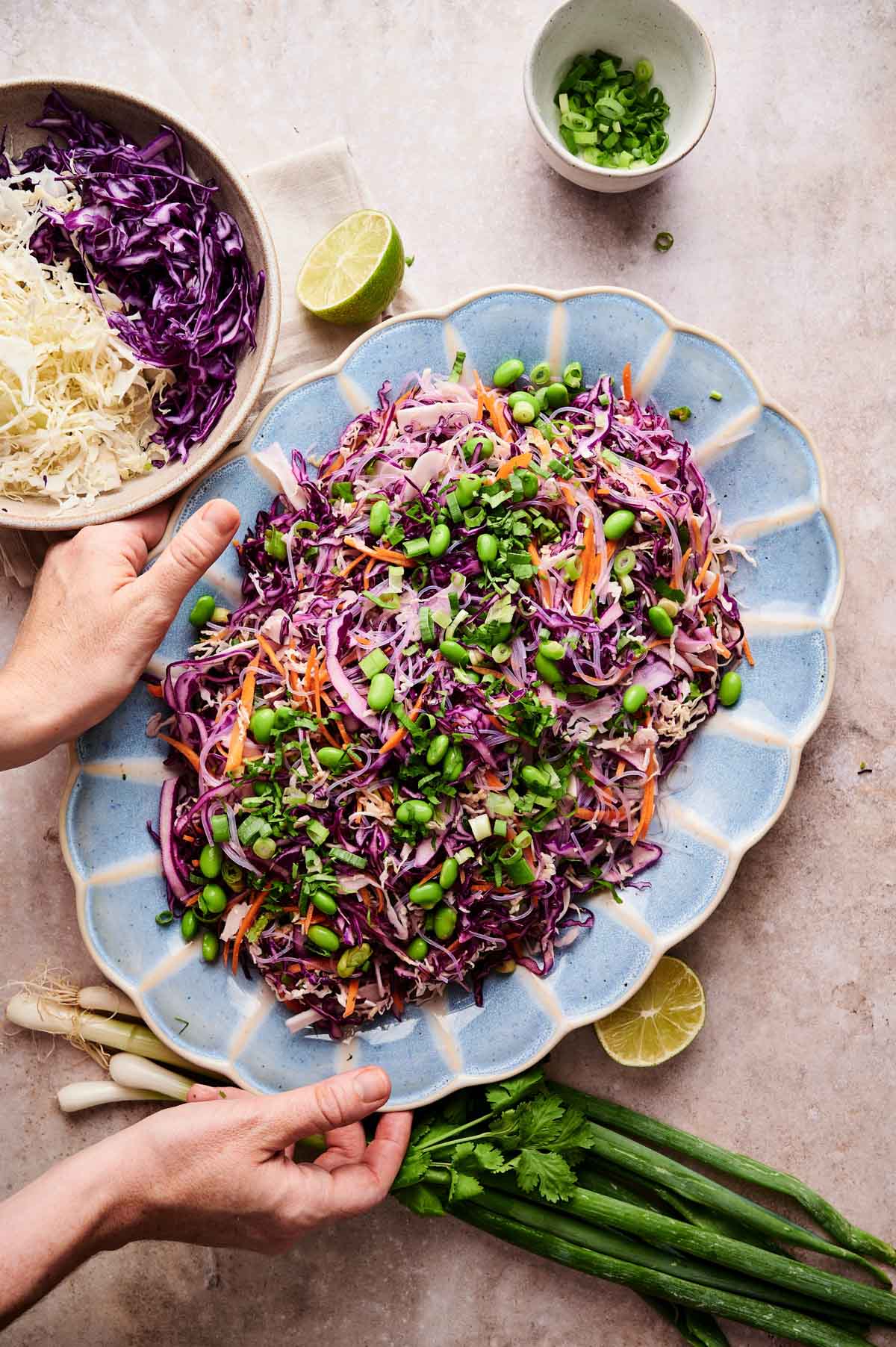 Woman reaching for a large platter of Asian rice paper roll salad.