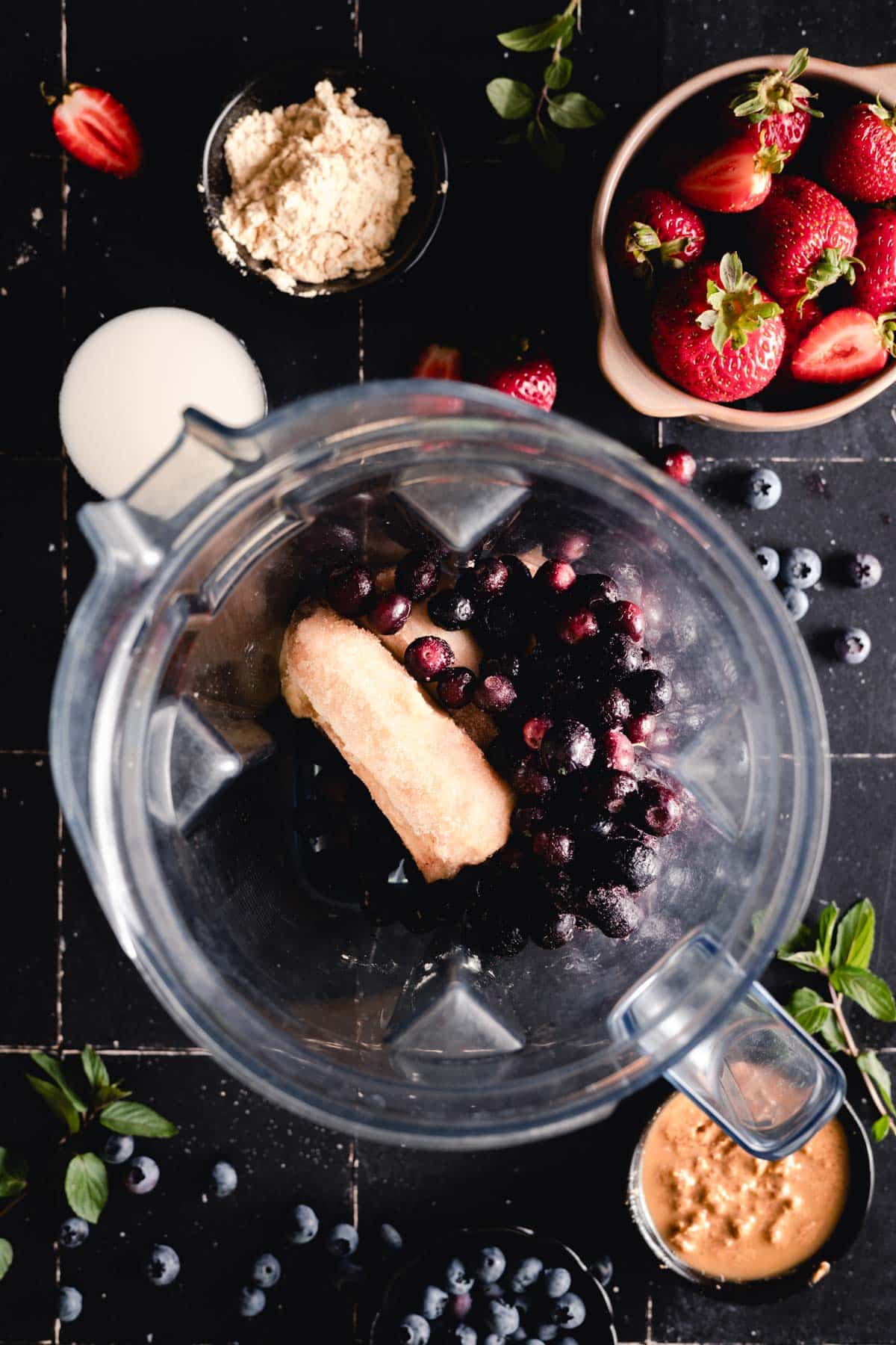Frozen bananas in a blender with frozen blueberries on top.