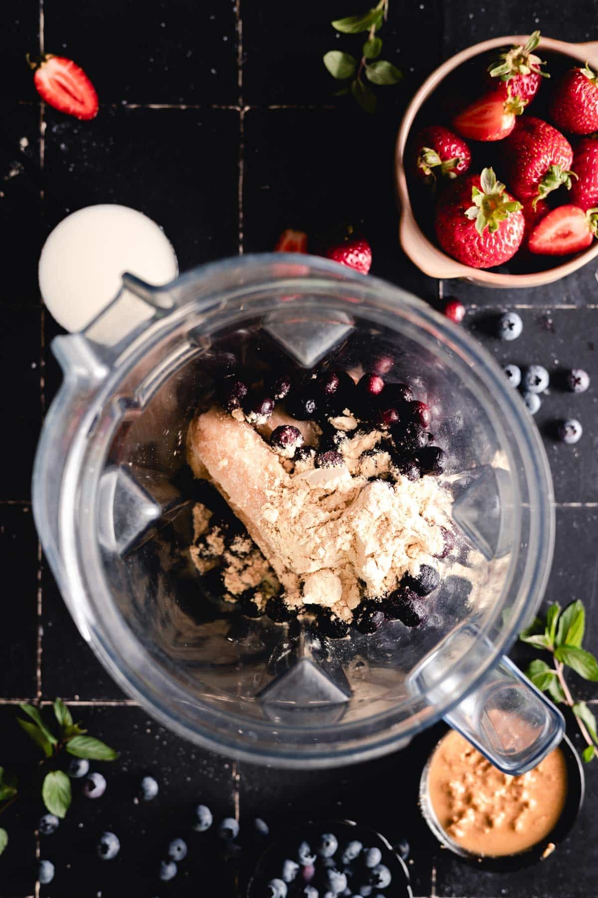 Frozen bananas, blueberries, and protein powder in a blender.