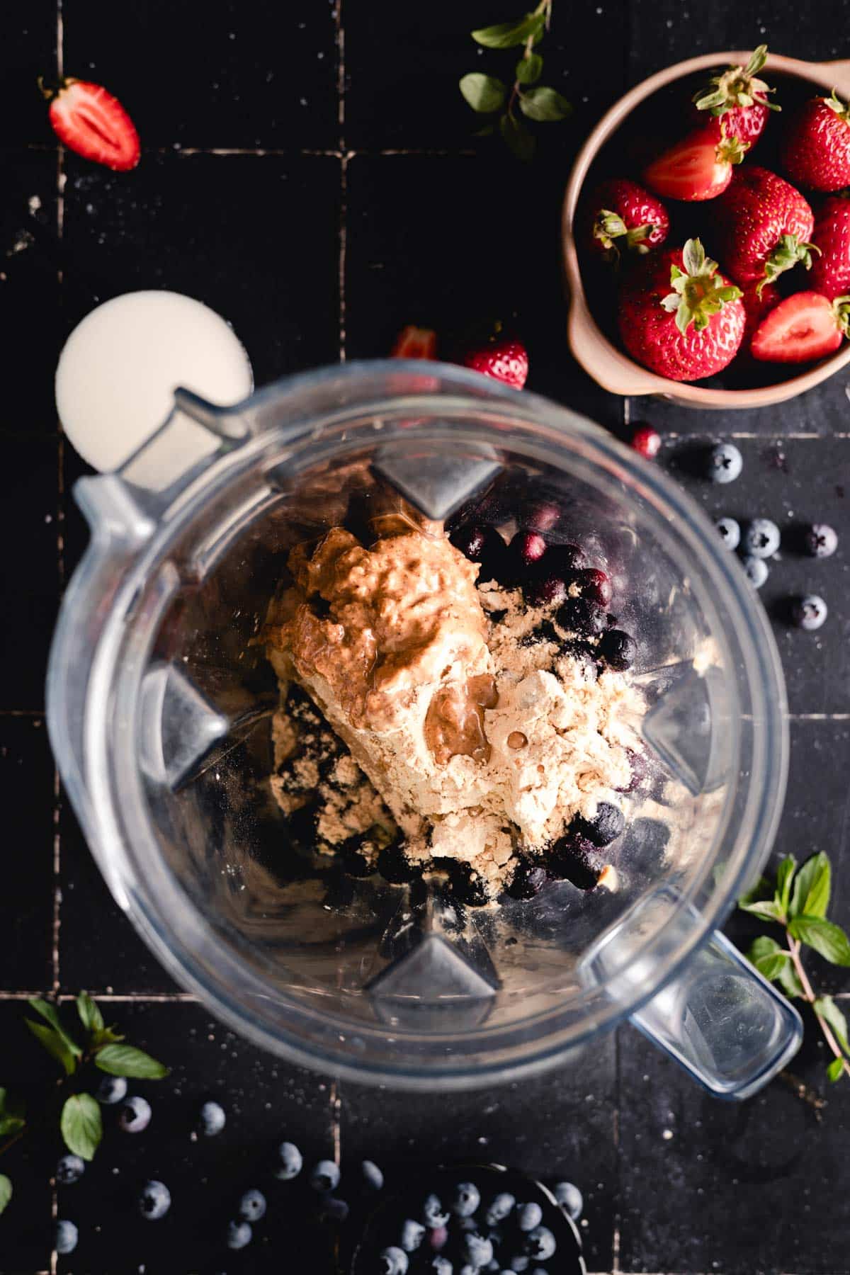 Frozen bananas, blueberries, protein powder, and almond butter in a blender.