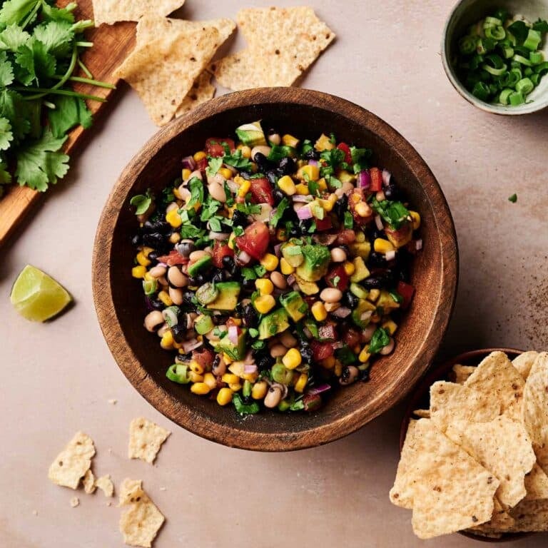 Healthy cowboy caviar on a cream counter with fresh ingredients next to it.
