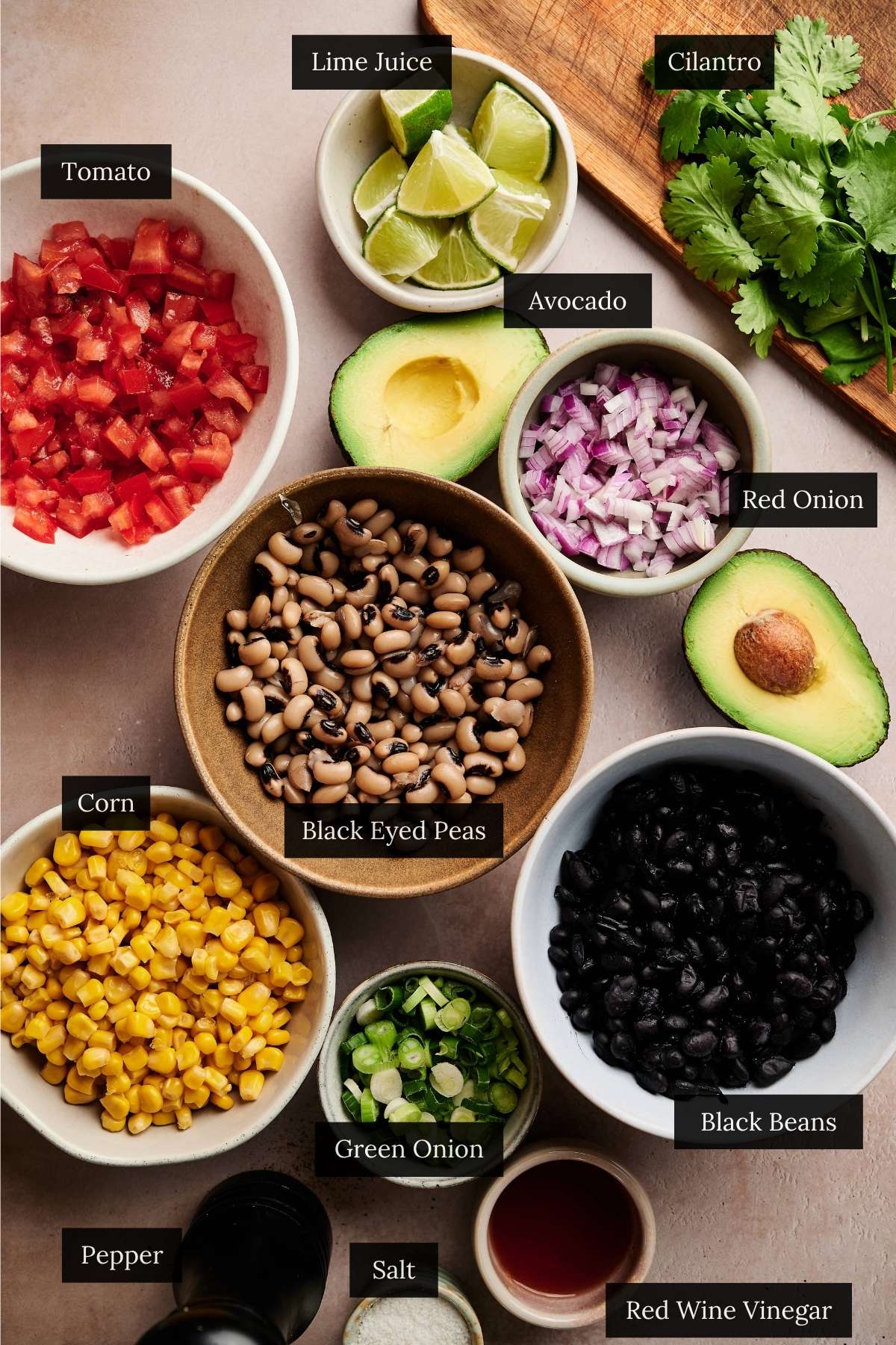 Ingredients for cowboy caviar on a cream counter all labeled.