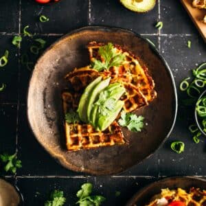 Vegan mashed potato waffle with sliced avocado on top.