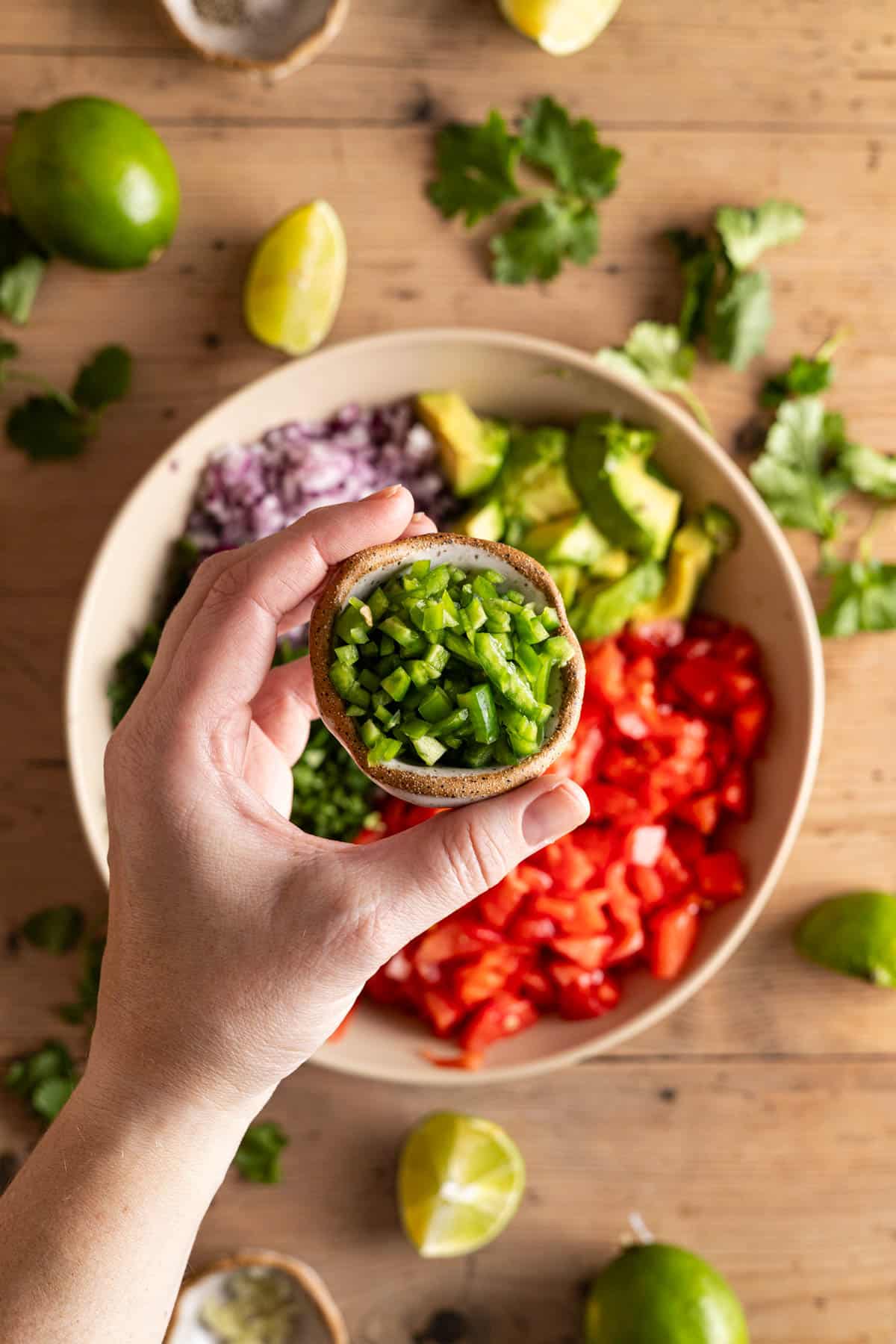 Chopped red onion, avocado, cilantro, and tomatoes added to a shallow bowl.