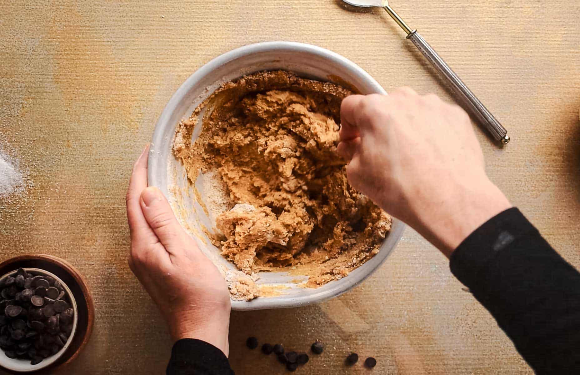 Combining the dry and wet ingredients in a large ceramic mixing bowl.