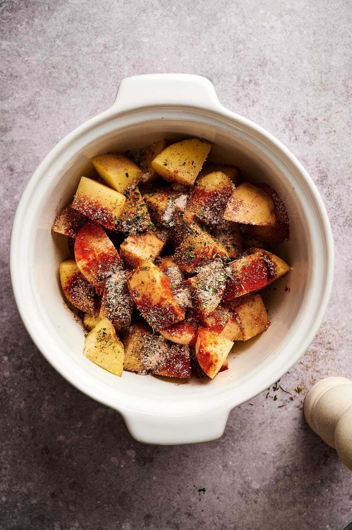 All of the ingredients for baked home fries in a white dish.