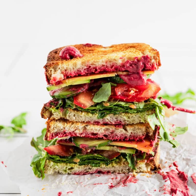 Hummus beet sandwich cut in half and stacked onto each other.