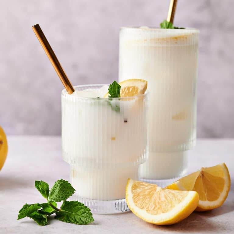 Fresh coconut lemonade with mint and sliced lemons next to it.