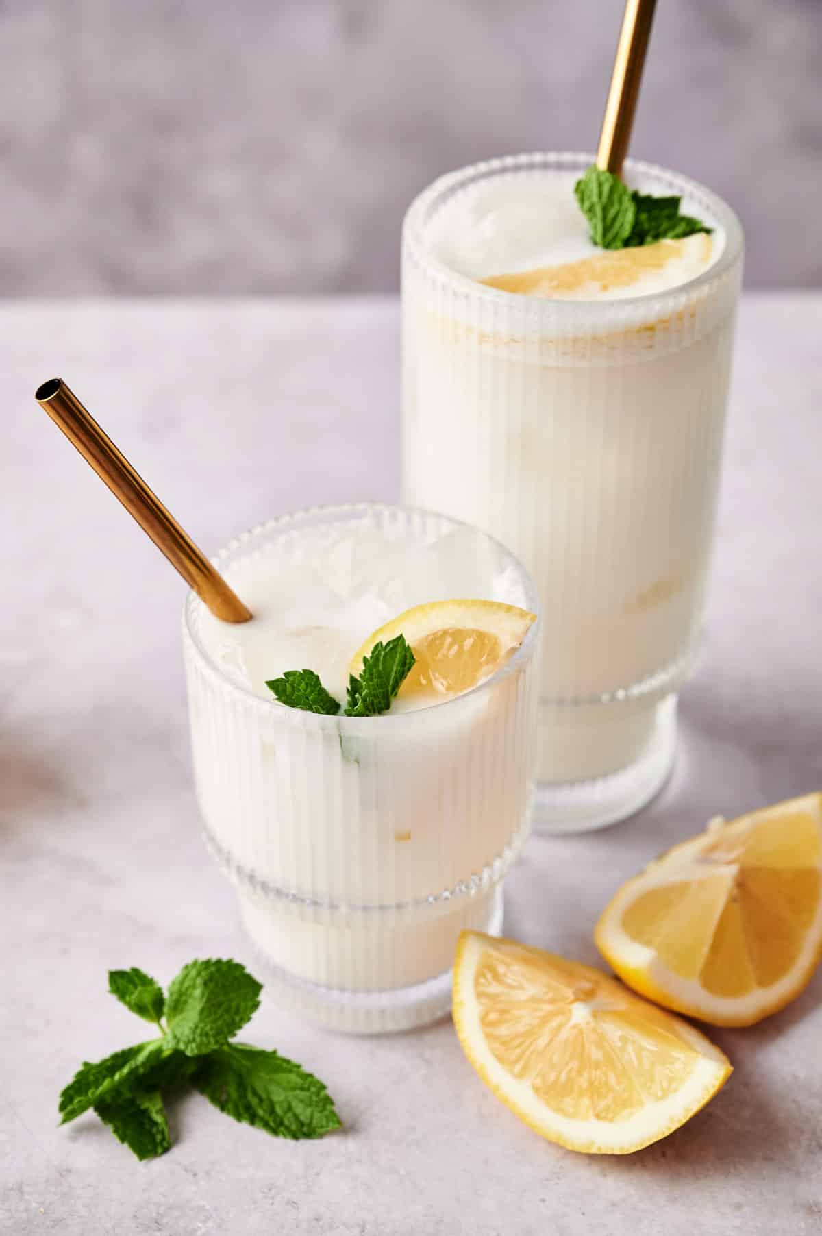 Fresh coconut lemonade with mint and sliced lemons next to it.