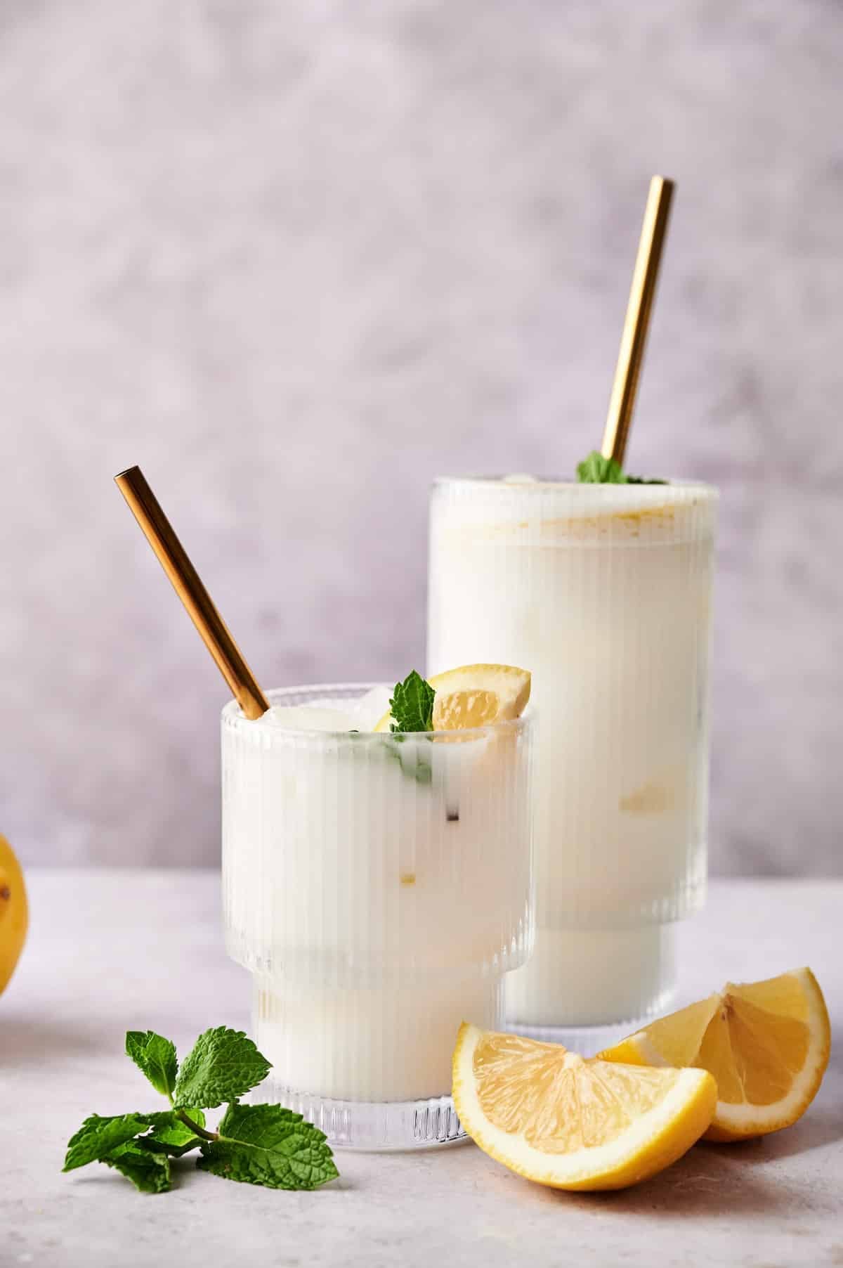 Fresh coconut lemonade with mint and sliced lemons next to it.