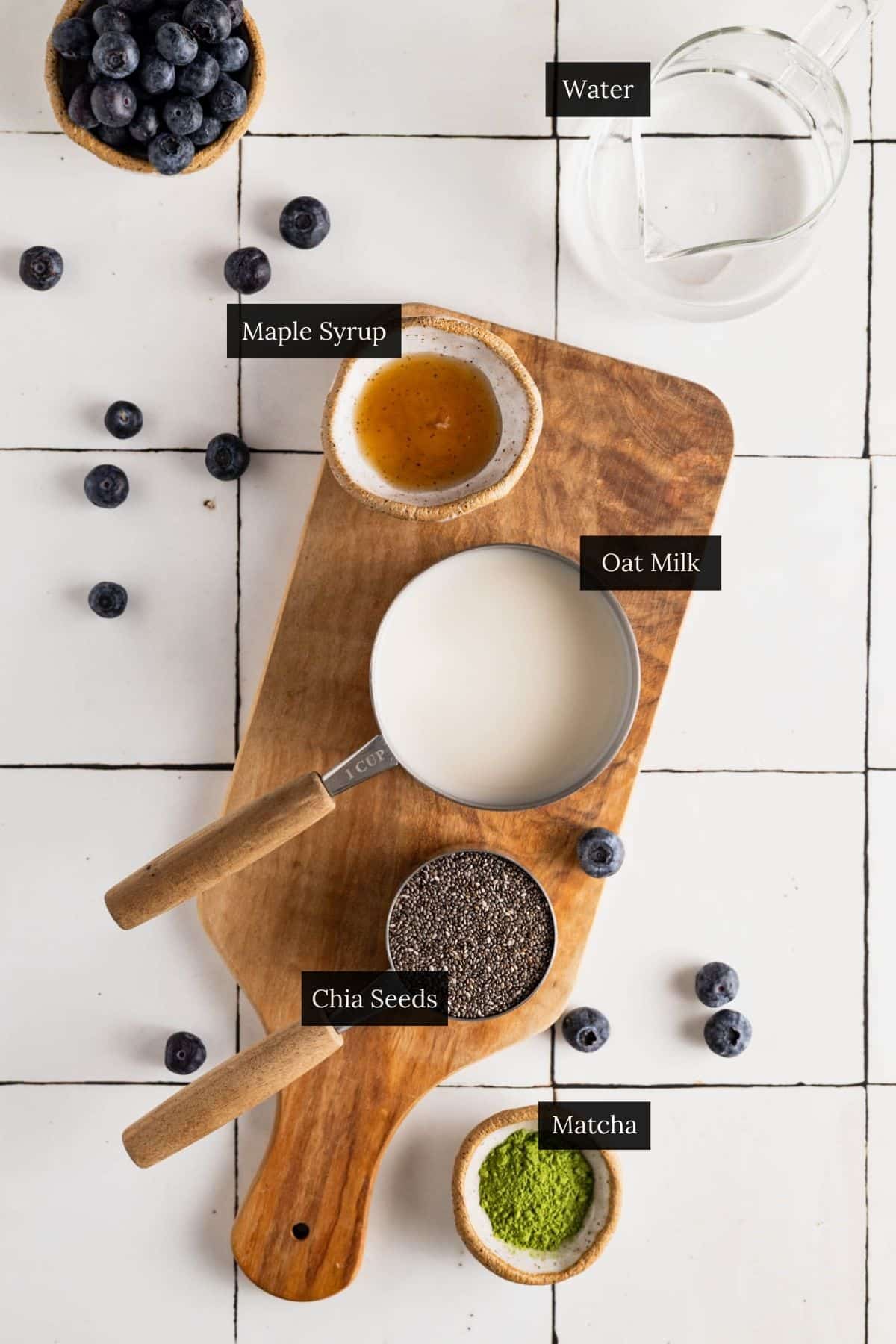 Ingredients for a matcha chia seed pudding recipe on a white tile counter with each ingredient labeled.