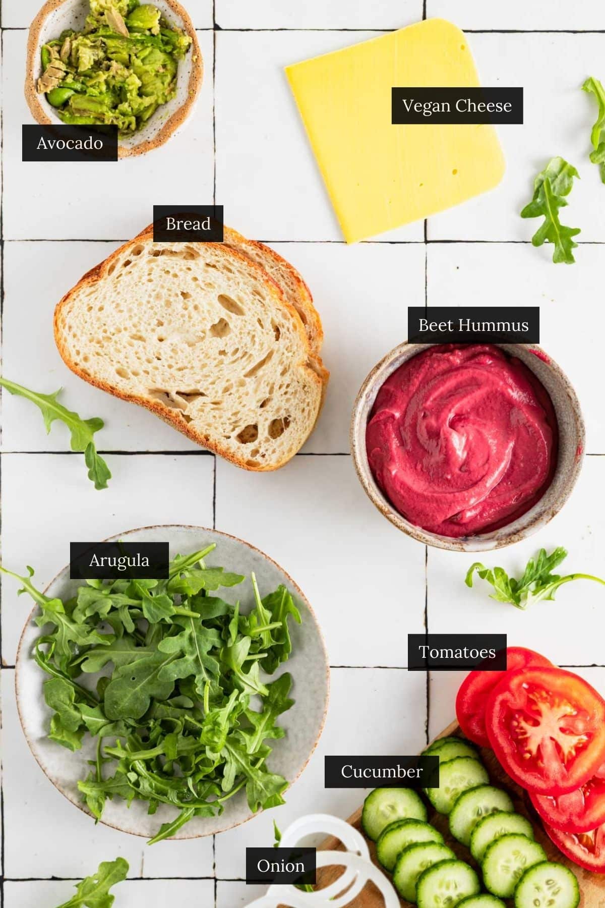 Ingredients for a tasty beetroot sandwich recipe on a white tile counter with each ingredient labeled.
