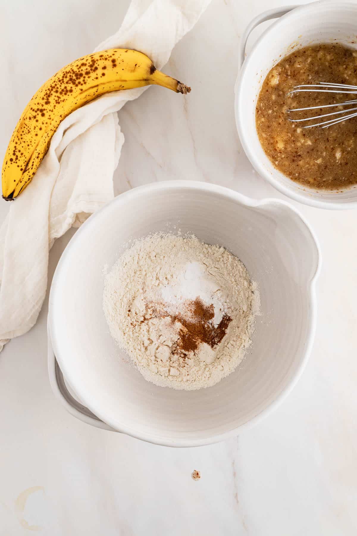 Adding dry ingredients to a medium mixing bowl and whisking them together.