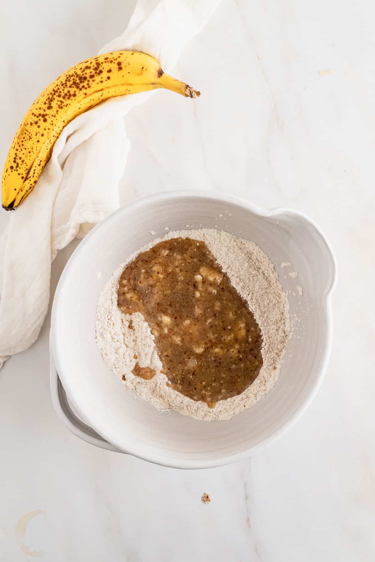 Pouring wet ingredients on top of dry ingredients and stirring until combined.