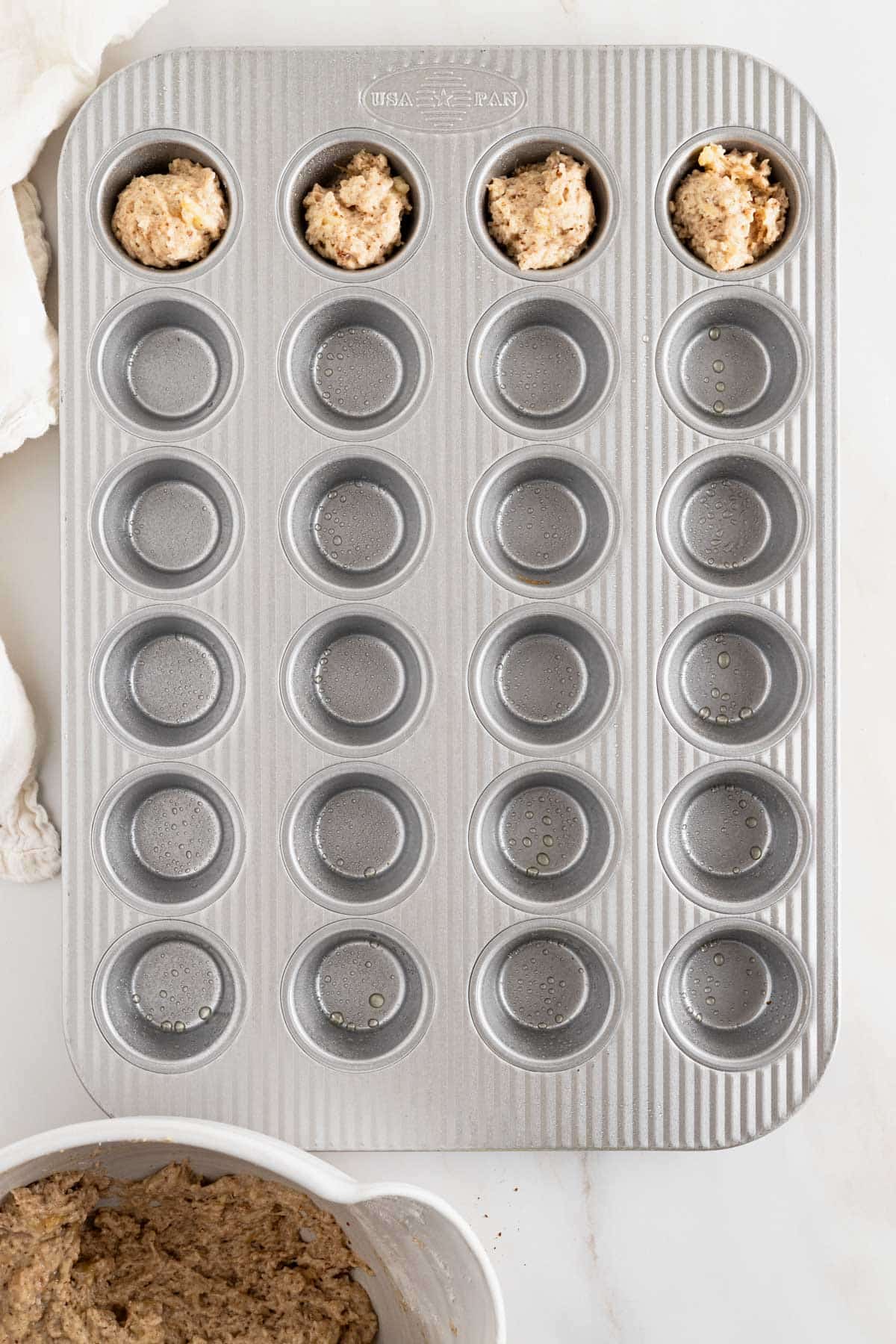 Banana bread muffin batter scooped into mini muffin pan.