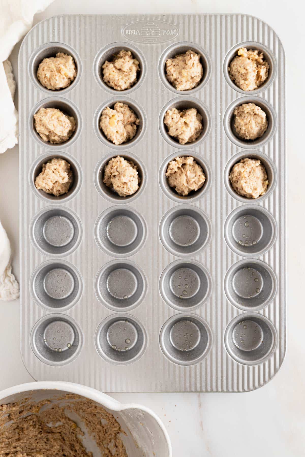 Banana bread muffin batter scooped into mini muffin pan.