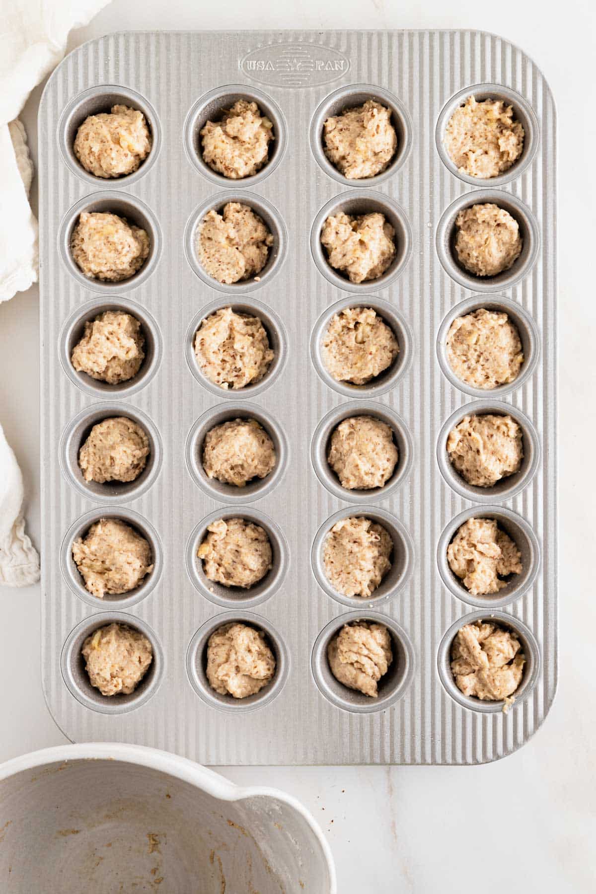 Banana bread muffin batter scooped into mini muffin pan.