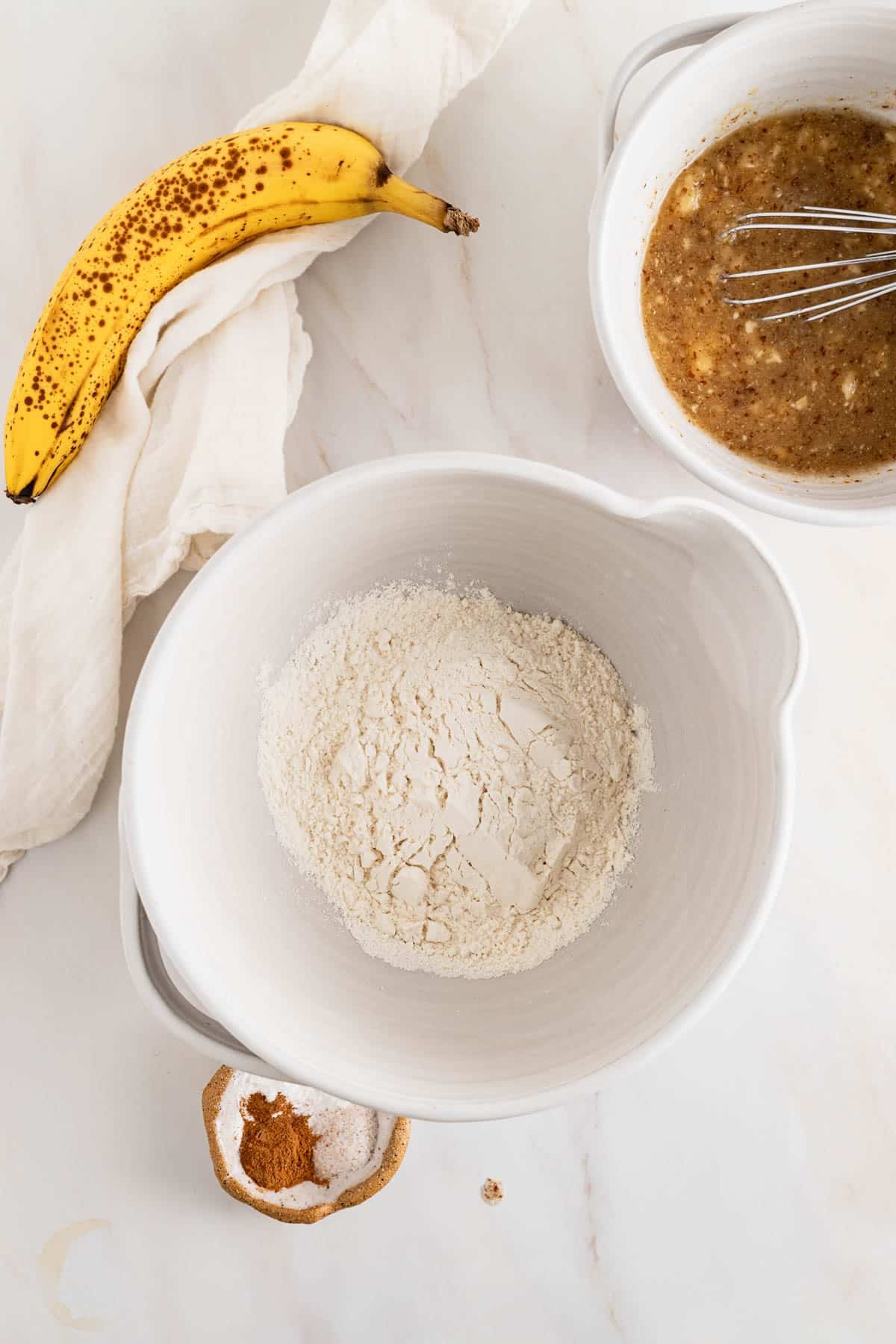 Adding dry ingredients to a medium mixing bowl and whisking them together.