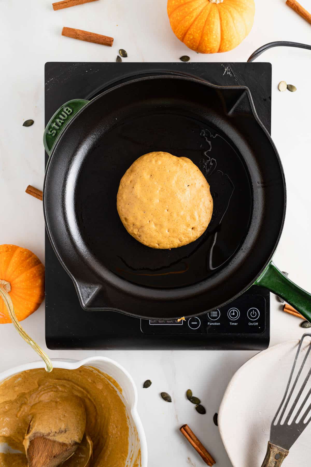 Cast iron skillet cooking pumpkin pancakes with protein powder.