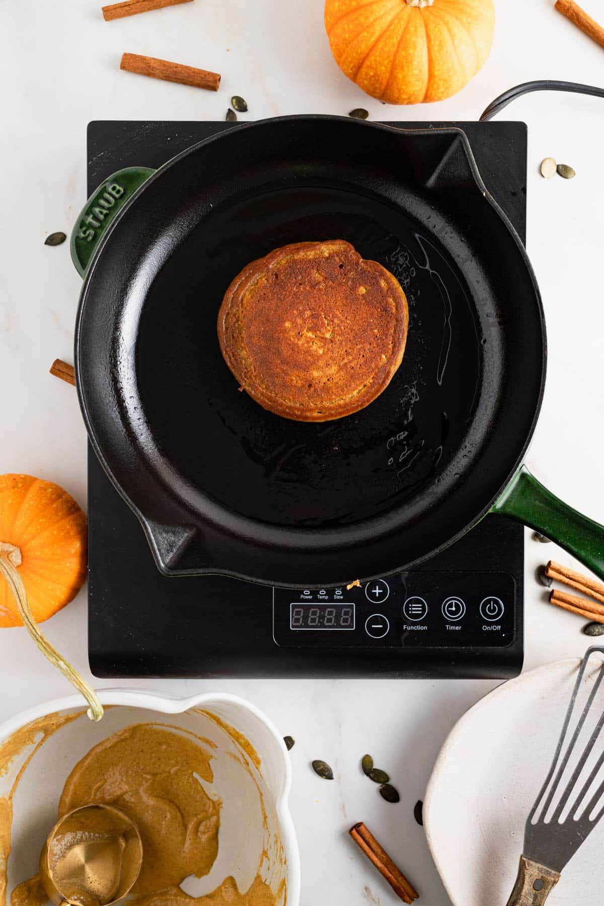 Cast iron skillet cooking pumpkin pancakes with protein powder.