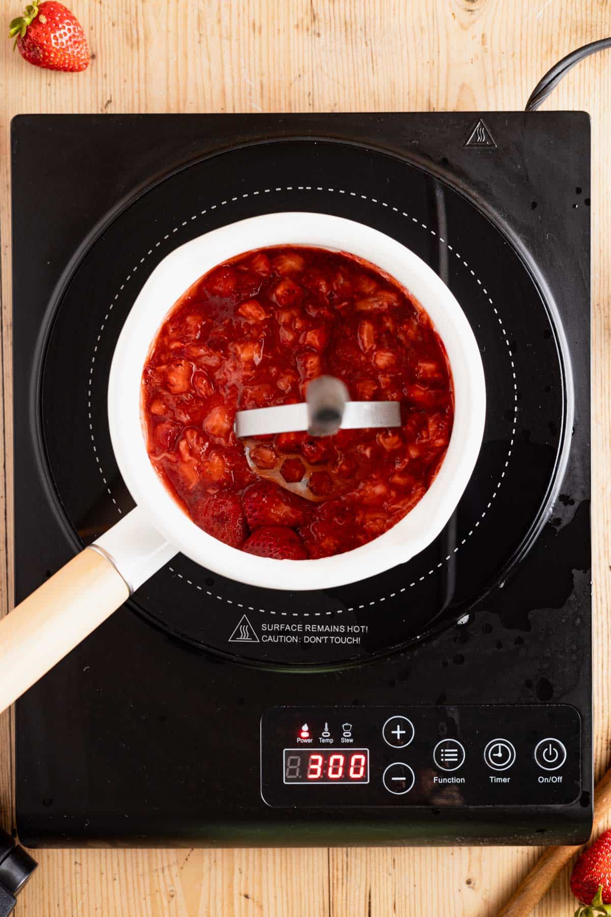 Mashing cooking strawberries.