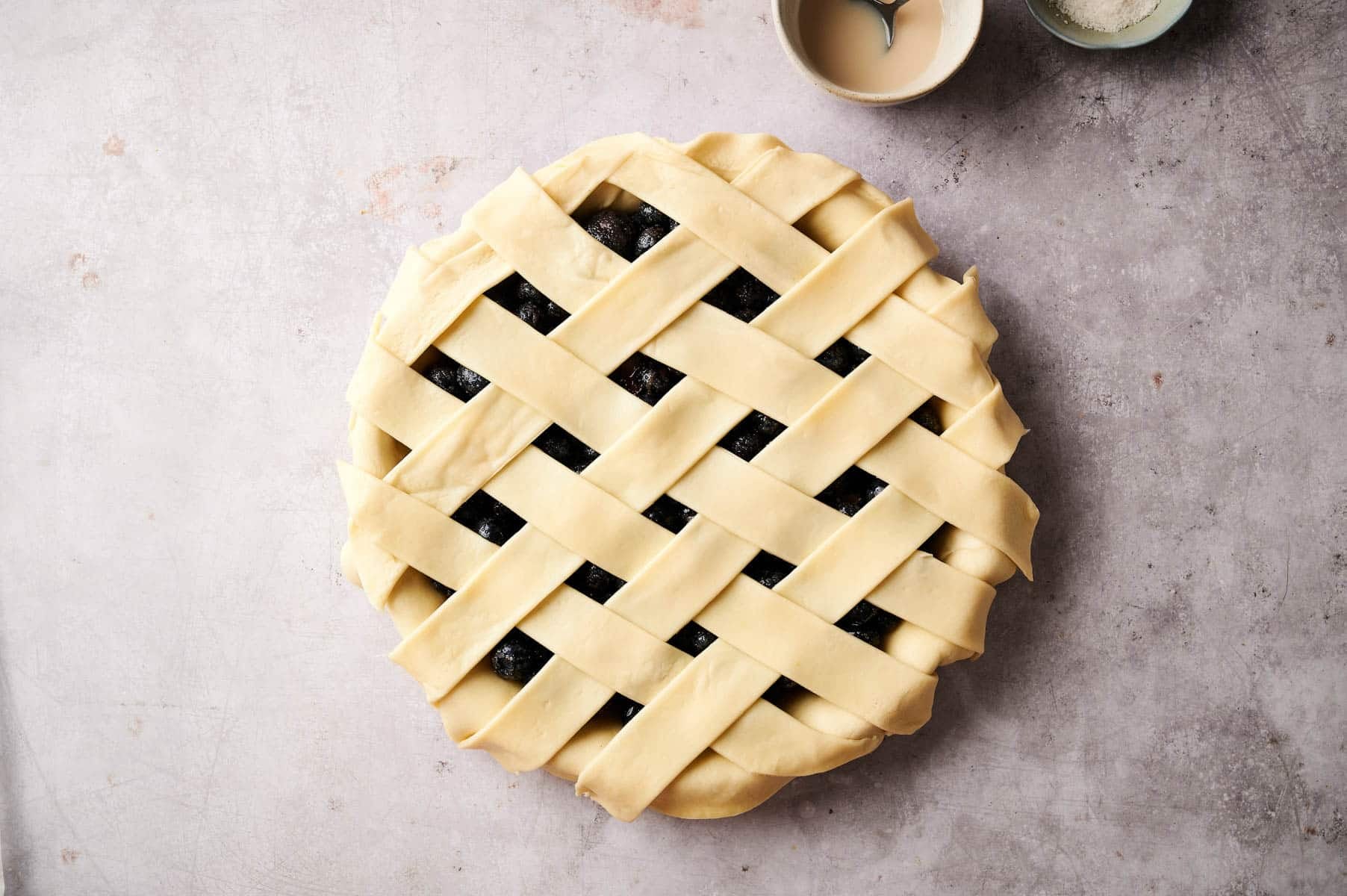 Creating pie crust lattice on top of the berry pie.