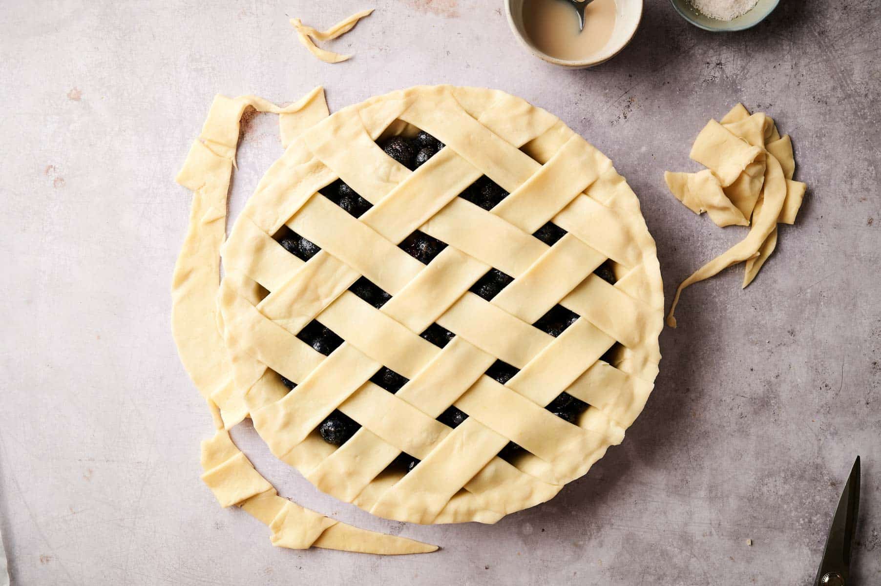 Creating pie crust lattice on top of the berry pie.