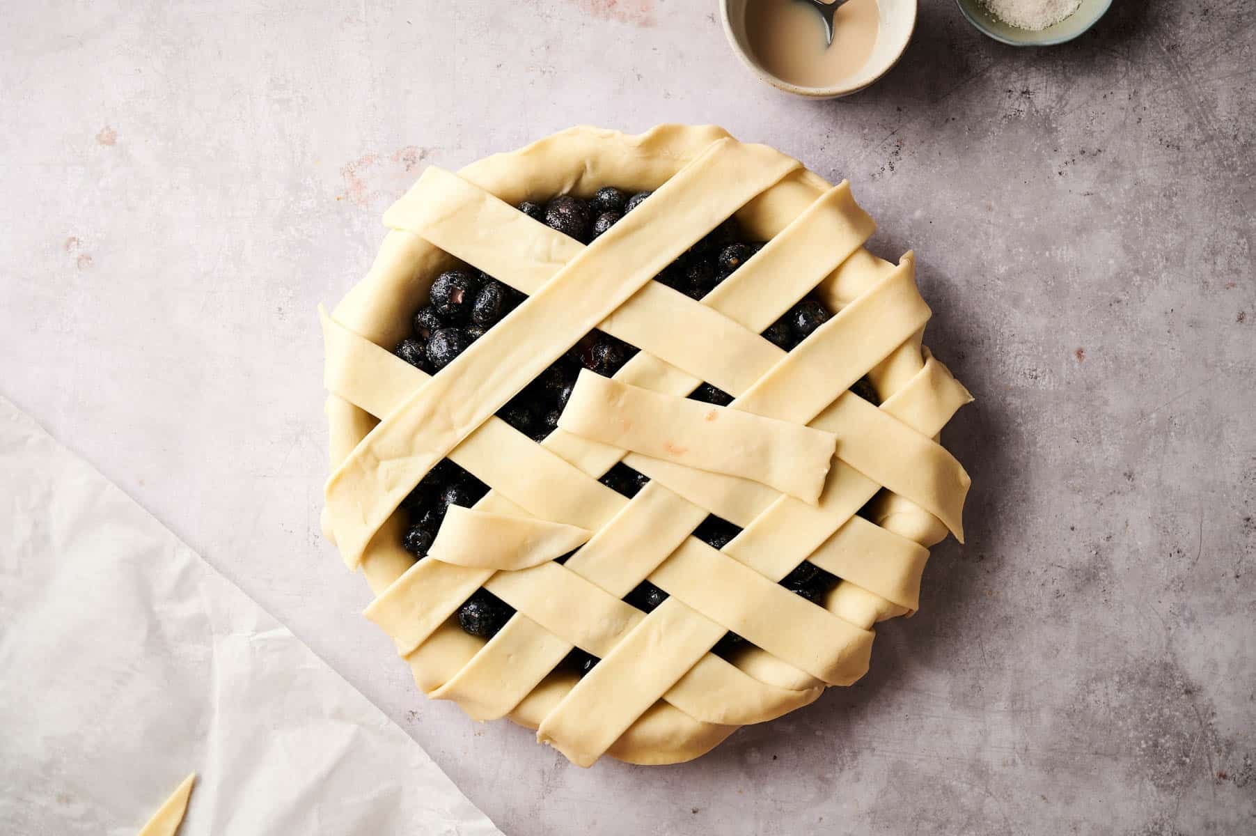 Creating pie crust lattice on top of the berry pie.