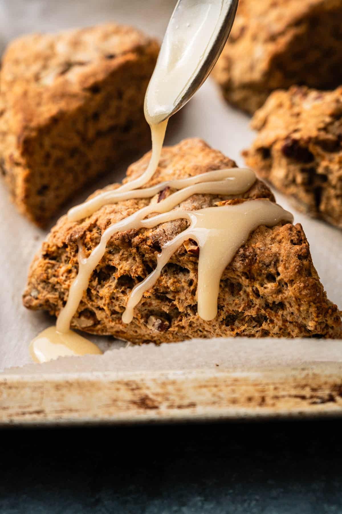 Maple glaze being drizzled on top of banana scones.