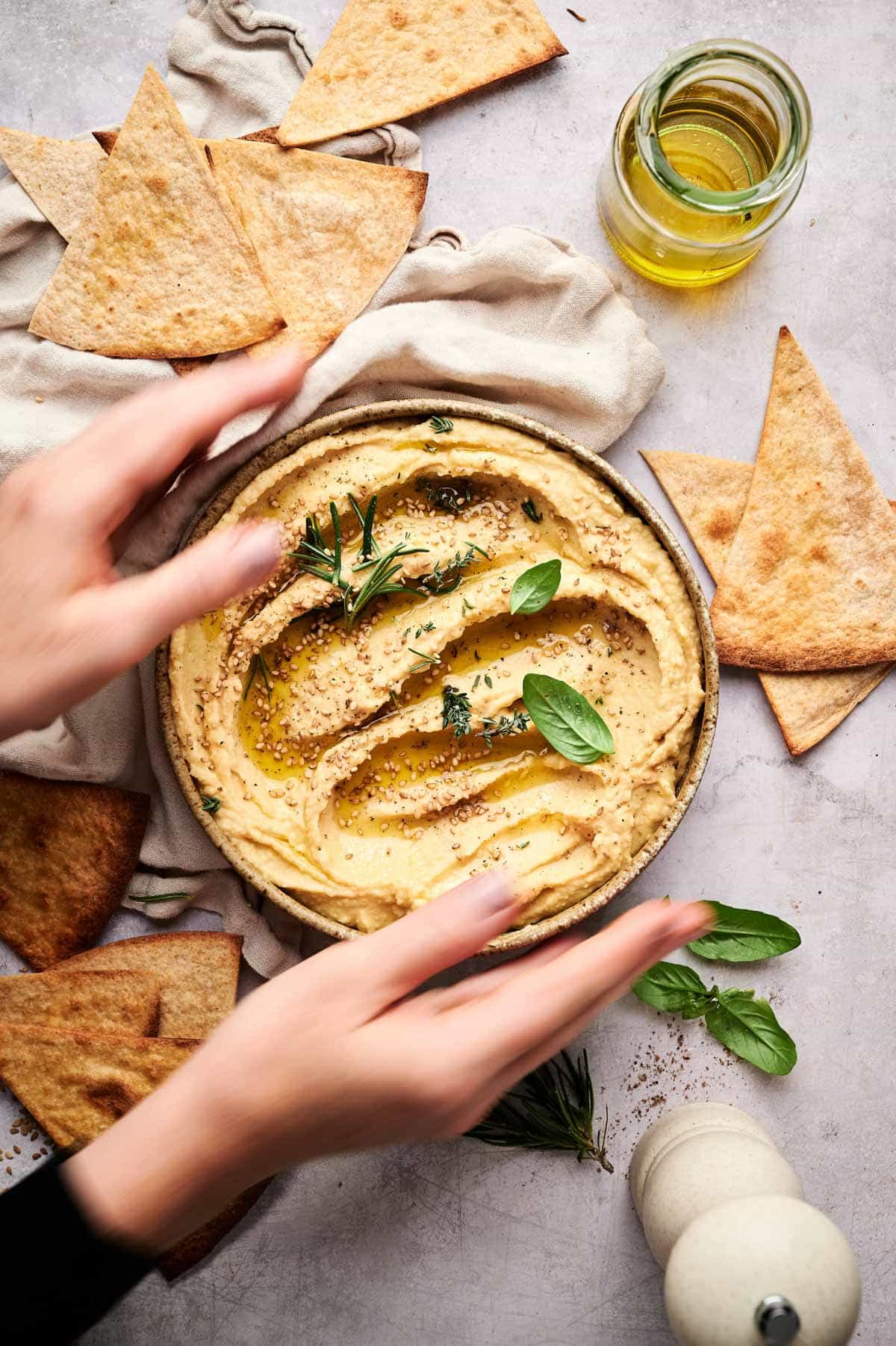 Woman reaching for a plate of homemade no tahini hummus.
