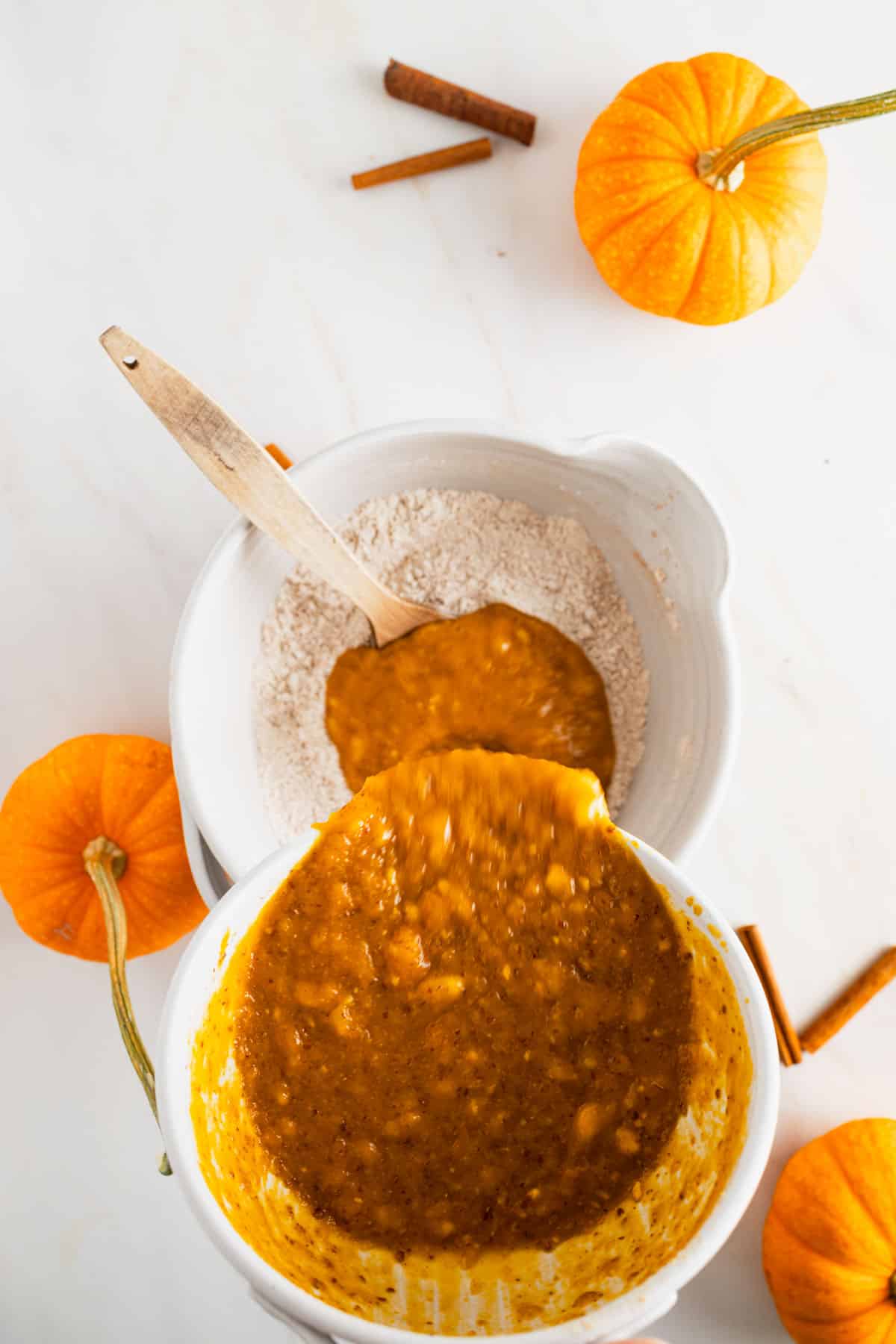 Wet ingredients for pumpkin muffins with banana added to a mixing bowl with dry ingredients.