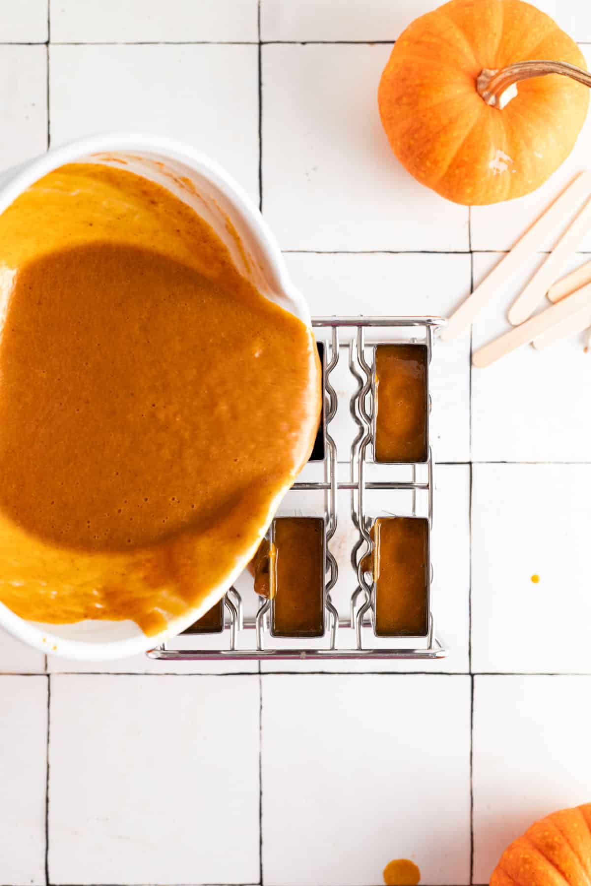 Pouring the pumpkin pie popsicle mixture into the stainless steel popsicle mold.