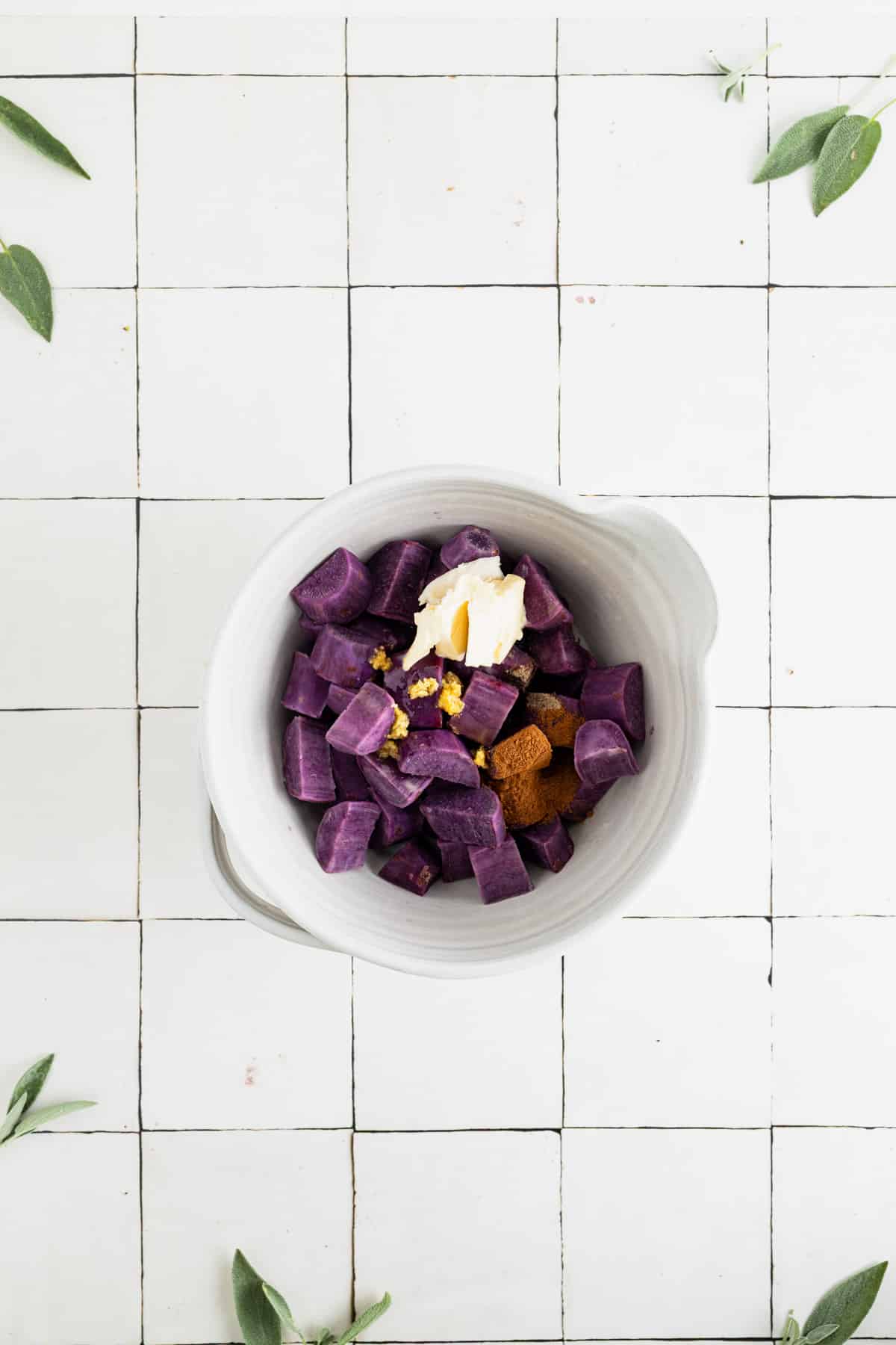 Sweet potatoes, spices, butter, and milk in a mixing bowl.