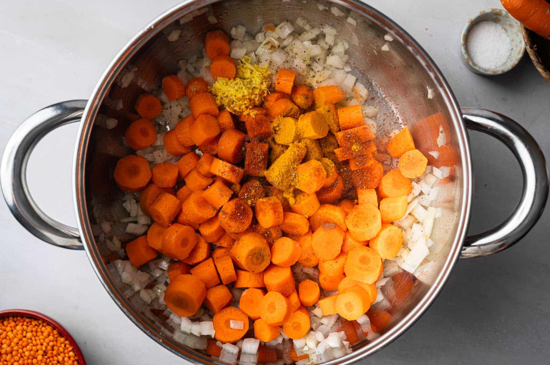 Sauteeing veggie for lentil and carrot soup in a stainless steel pot.