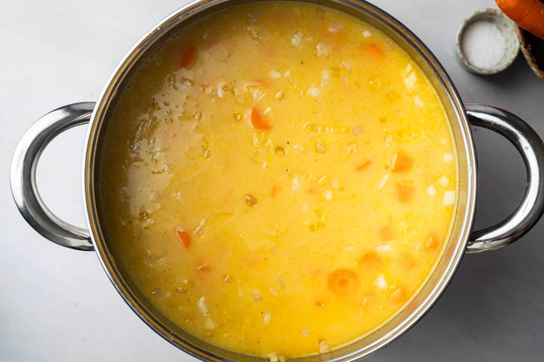 Veggies, lentils, and carrots cooking in the stainless steel pot.