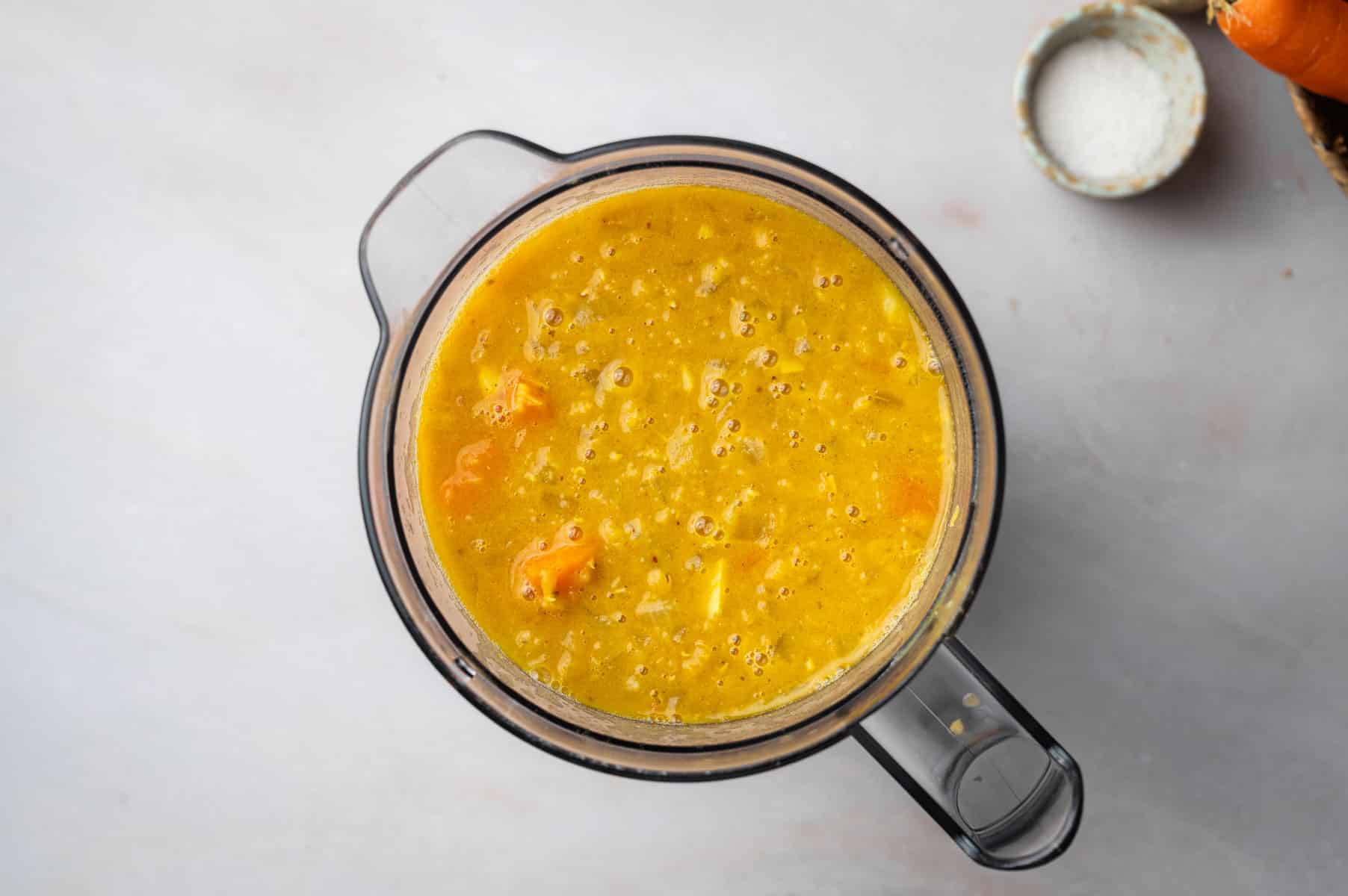 Lentil and carrot soup added to a blender and pureed.