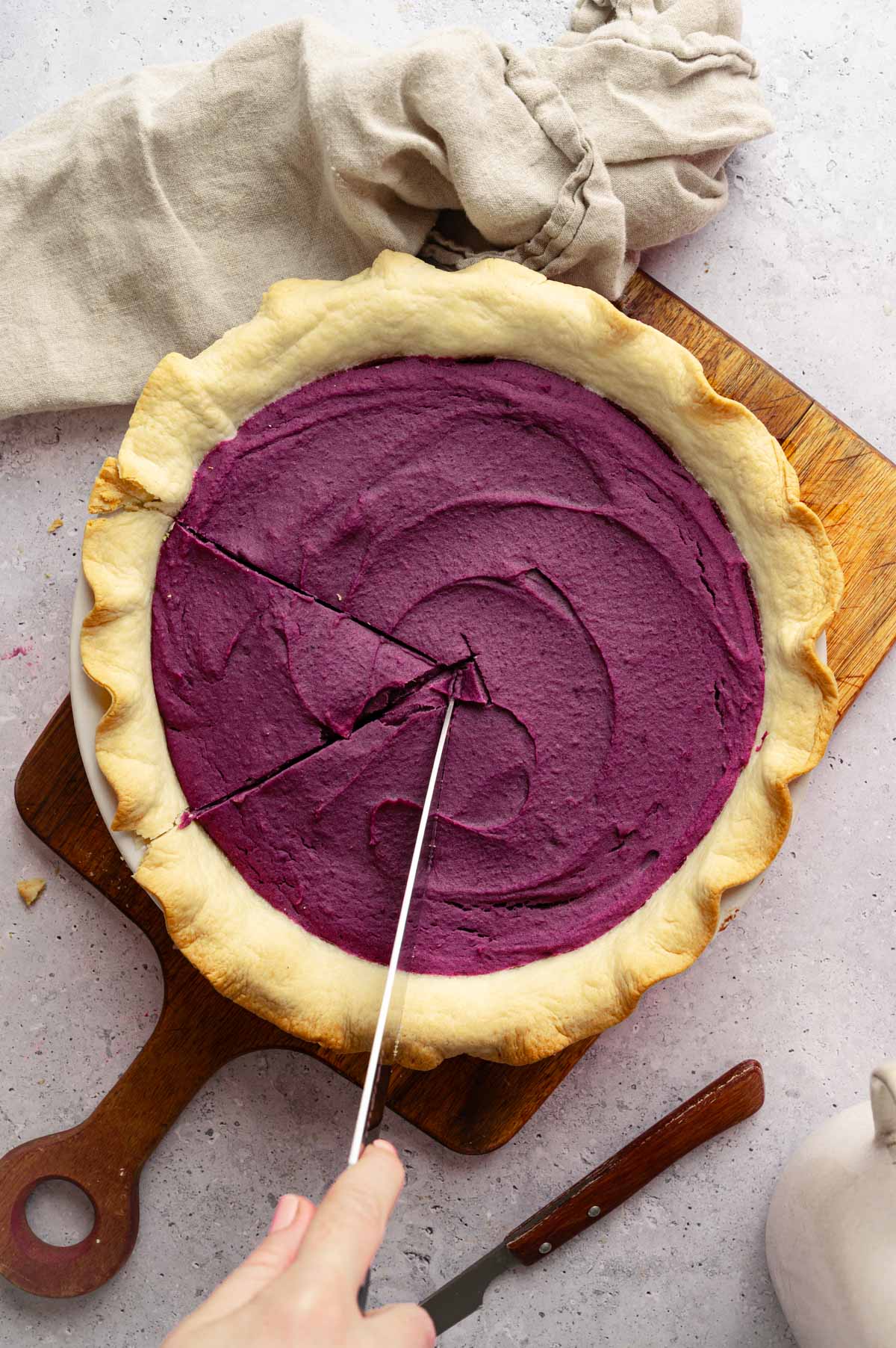 Woman cutting purple sweet potato pie.
