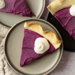 Homemade vegan sweet potato pie slices on plates with whipped cream.