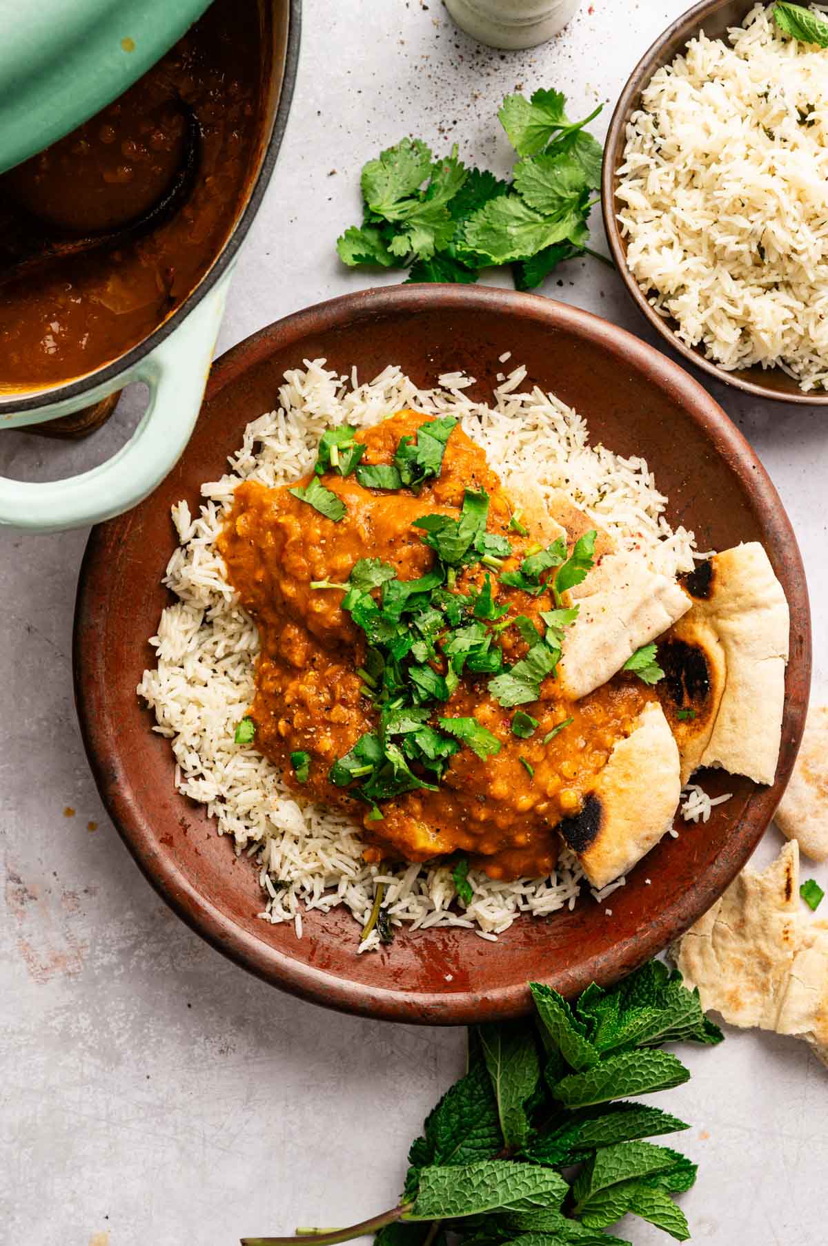 Homemade vegan tikka masala in a shallow bowl with rice and fresh herbs on top.