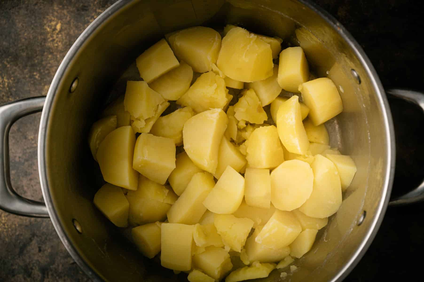 Boiled potato cubes in a stainless steel soup pot.