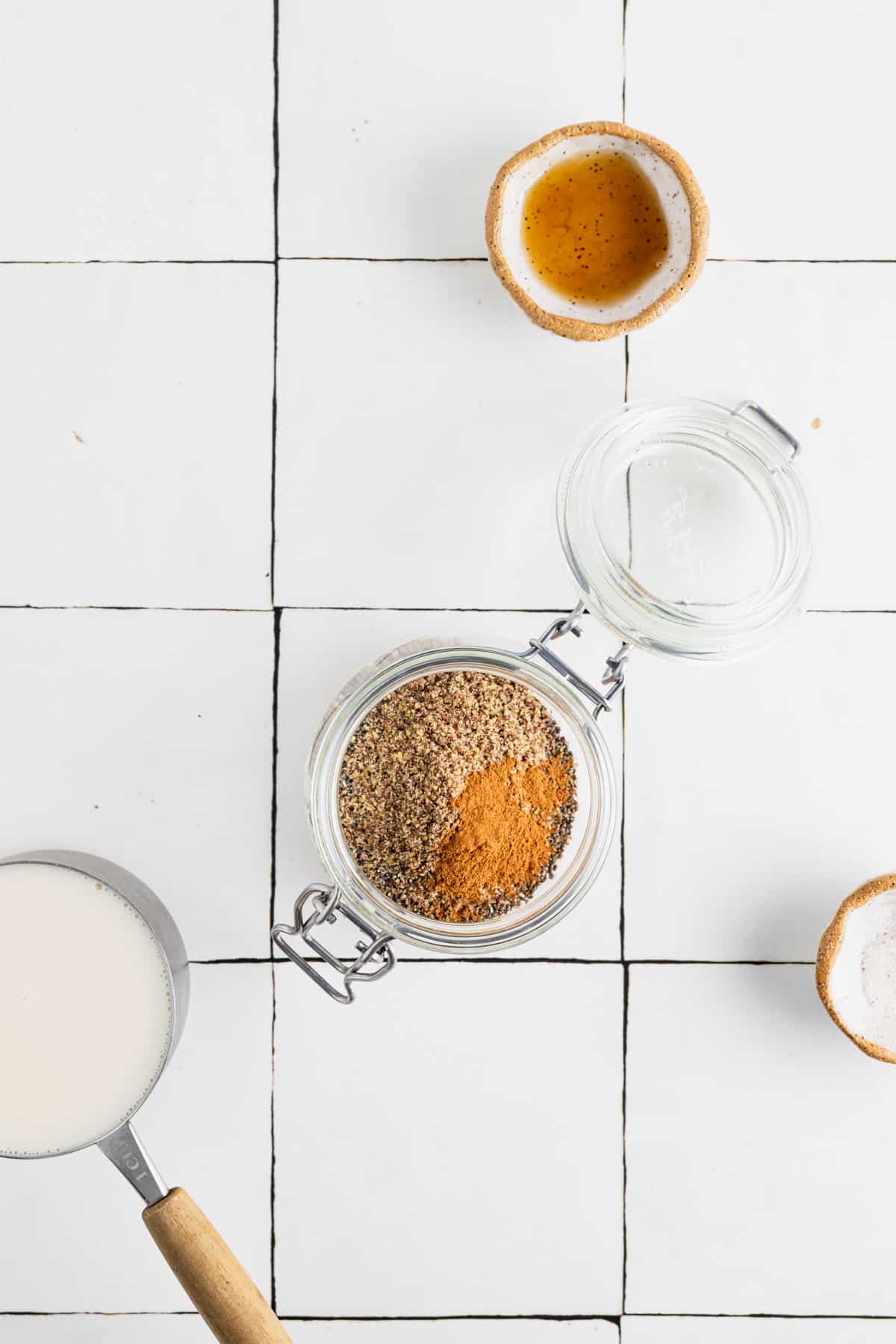 Adding the dry ingredients for chia and flax seed pudding to a clear glass jar.