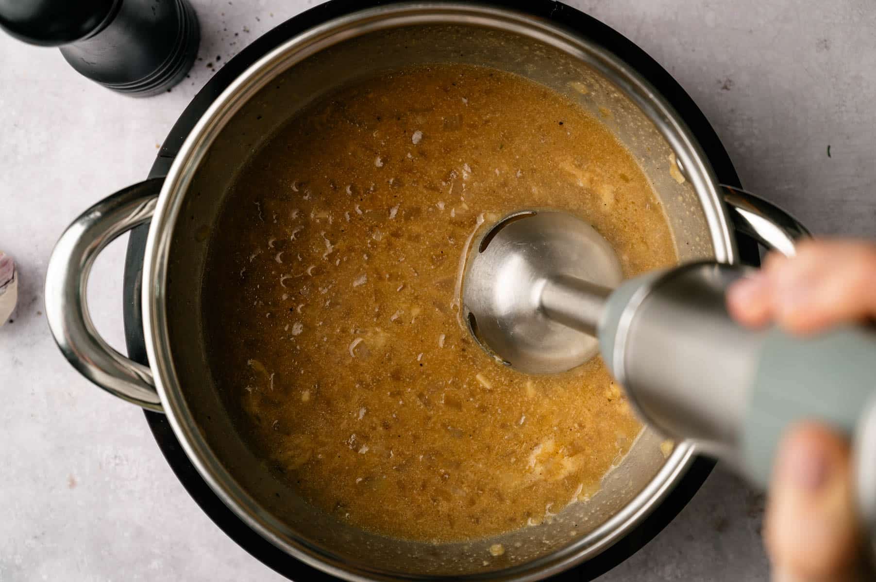 Immersion blender going into the soup pot blending the ingredients together.