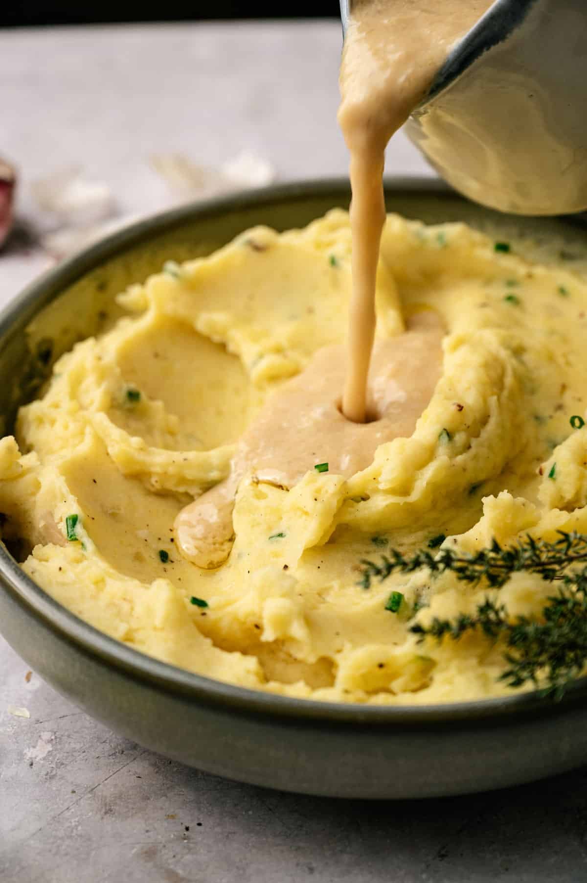 Gravy being poured over mashed potatoes.