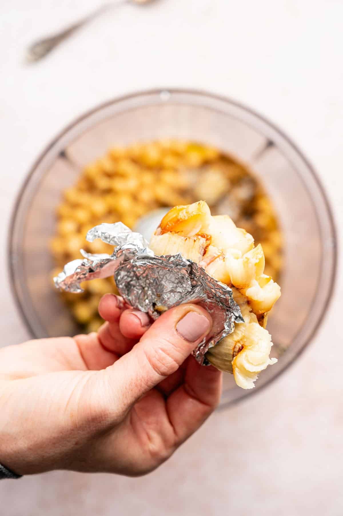 Roasted garlic being squeezed into food processor.