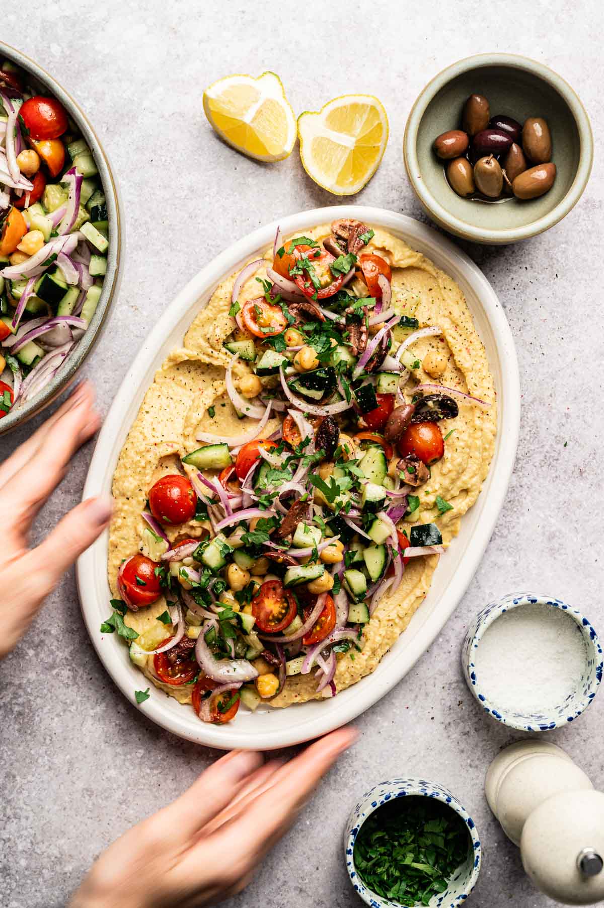 Woman reaching for loaded hummus platter.