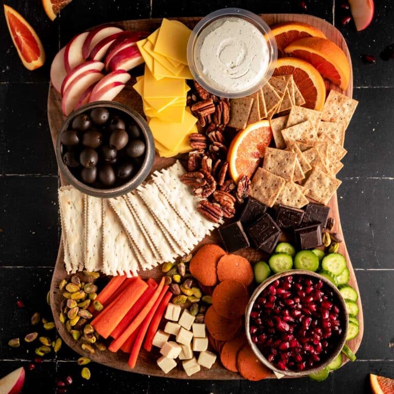 Chocolate and nuts added next to the fruits, veggies, crackers, and vegan cheeses.