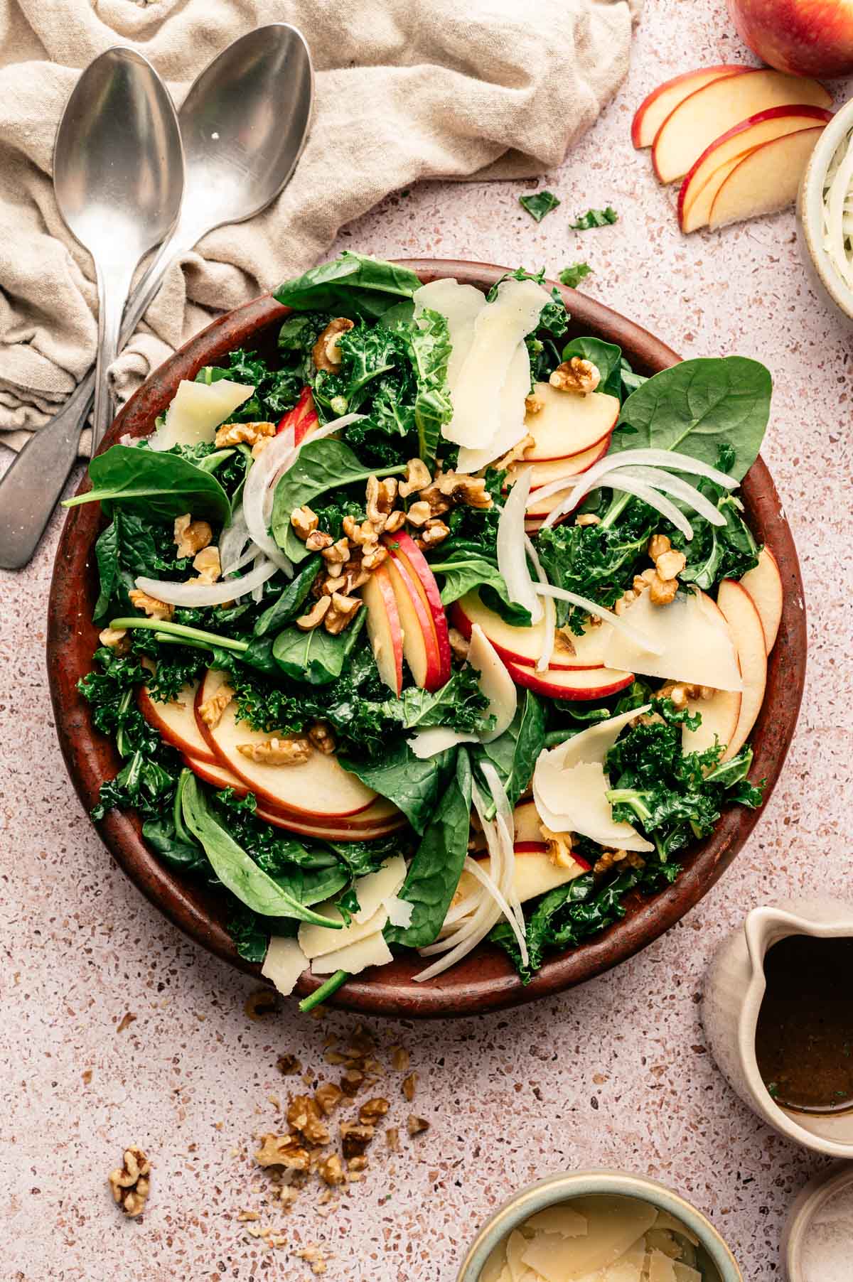 Spinach and kale salad with sliced apples, vegan parm, onion, and more.