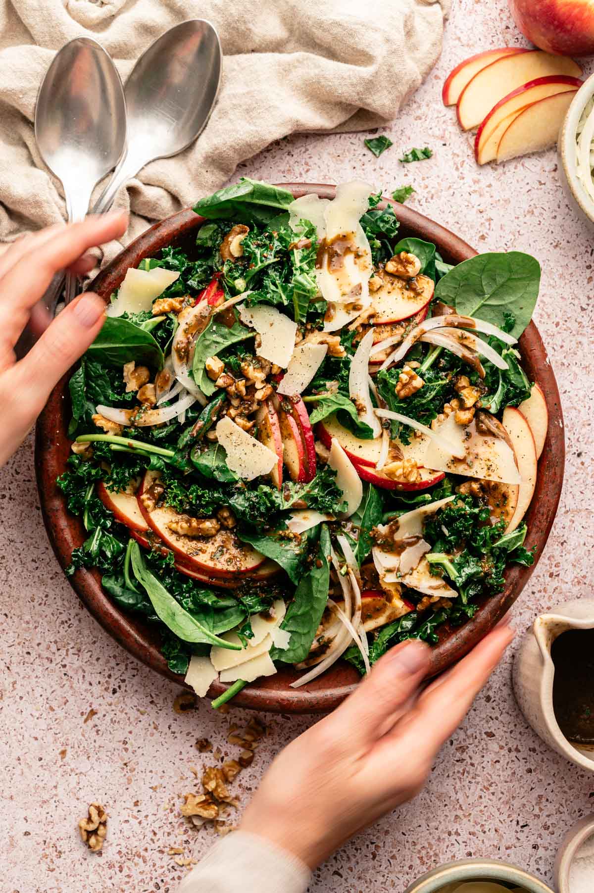 Spinach and kale salad with sliced apples, vegan parm, onion, and more.