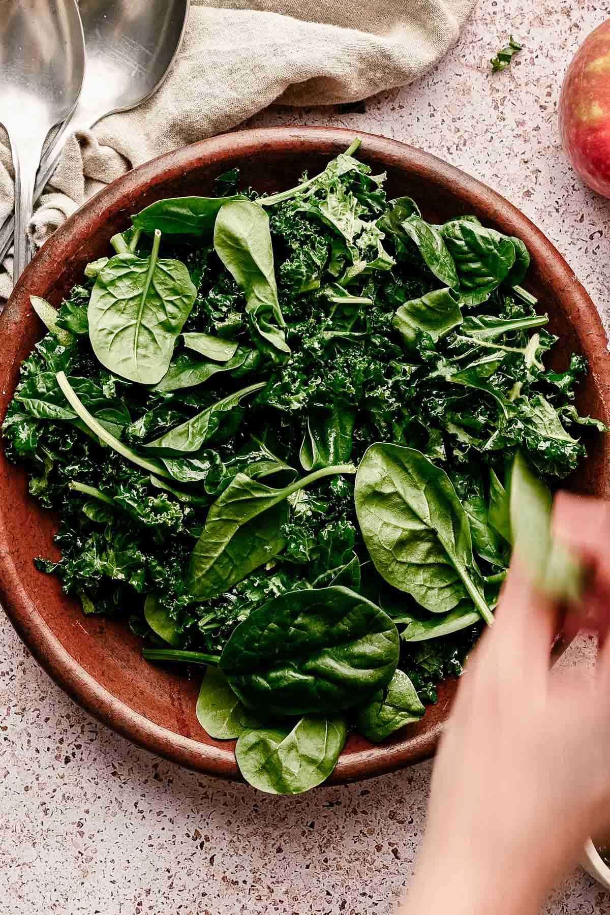 Adding spinach to the plate of kale.
